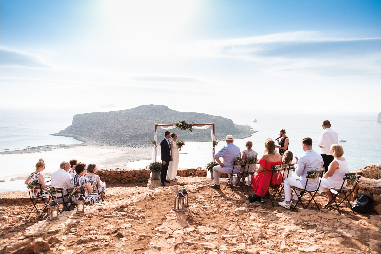 Mariage intimiste Love Explorers en plein air face à la mer en France, arche fleurie et invités en tenue claire